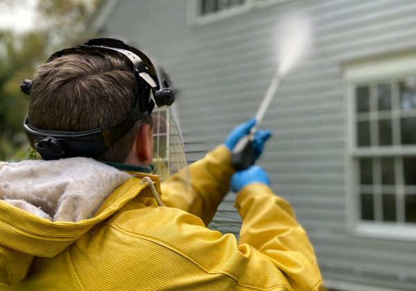 Worker pressure washing the exterior of a house
